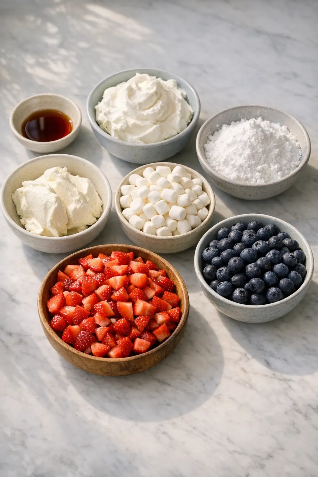 Ingredients for a red, white, and blue dessert salad: cream cheese, powdered sugar, whipped topping, mini marshmallows, strawberries, blueberries